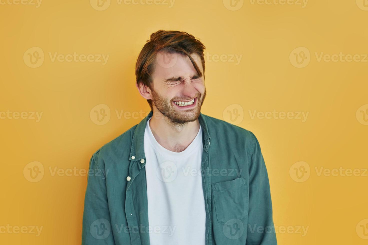 sur fond jaune. jeune homme en vêtements décontractés debout à l'intérieur dans le studio photo