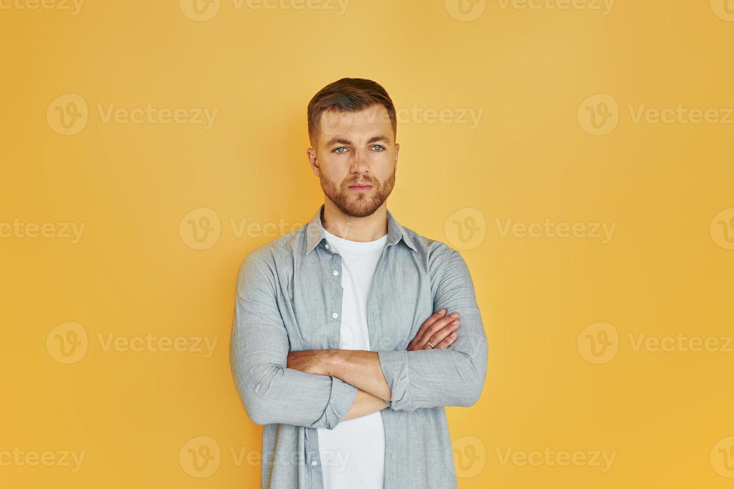 jeune homme en vêtements décontractés debout à l'intérieur dans le studio sur fond orange photo