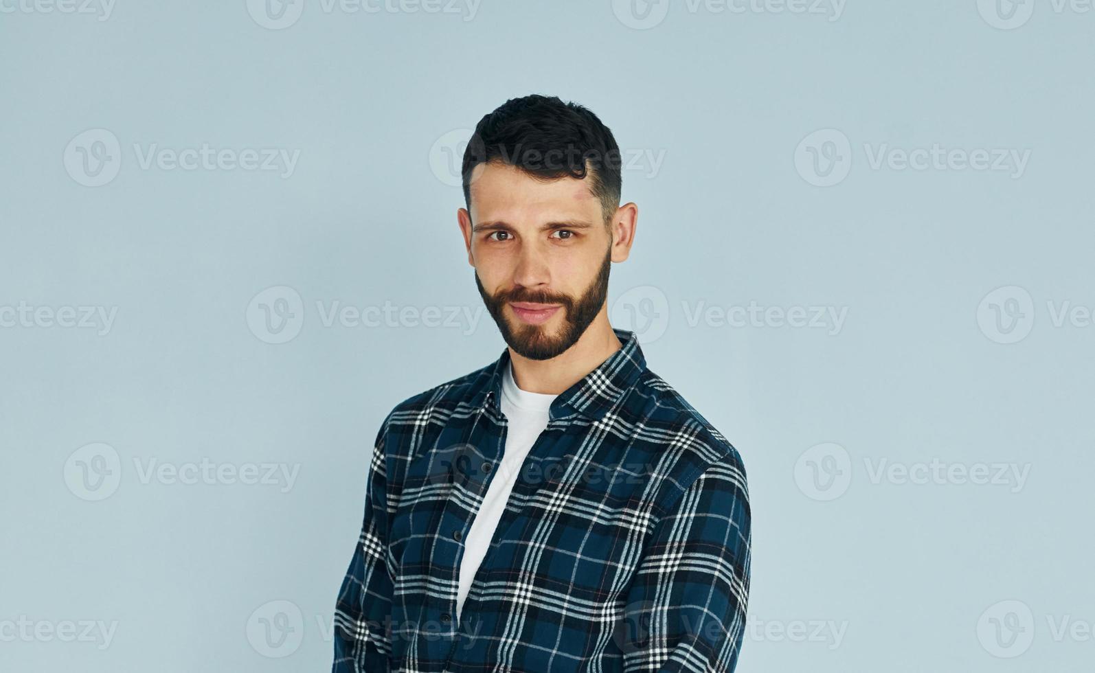 regarde dans la caméra. jeune homme en vêtements décontractés debout à l'intérieur dans le studio photo