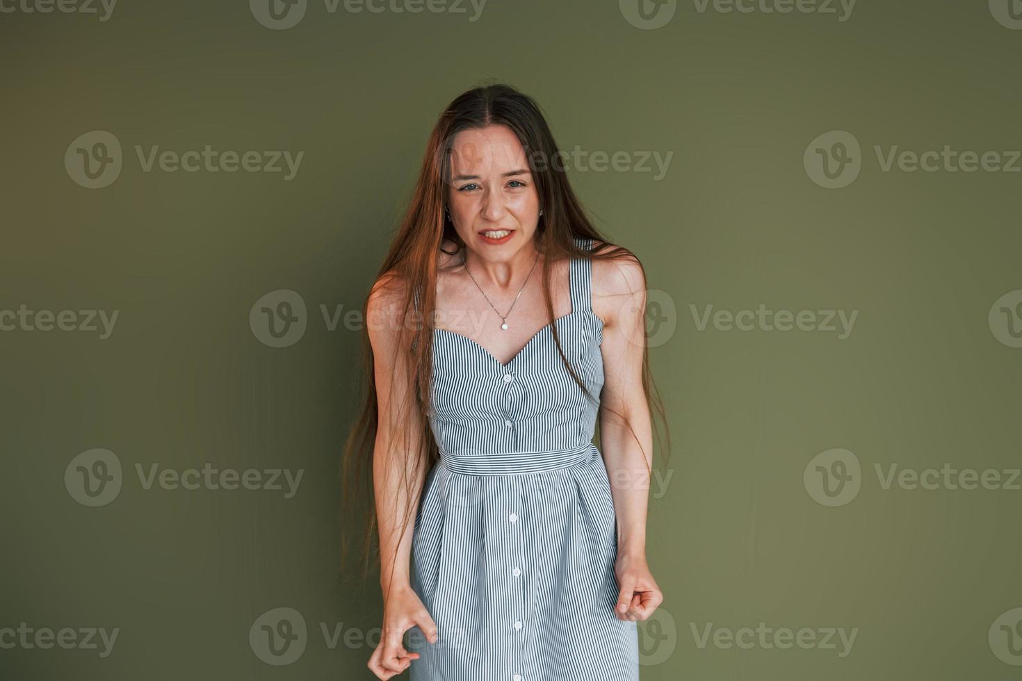 expression faciale. jeune femme en vêtements décontractés debout à l'intérieur dans le studio photo