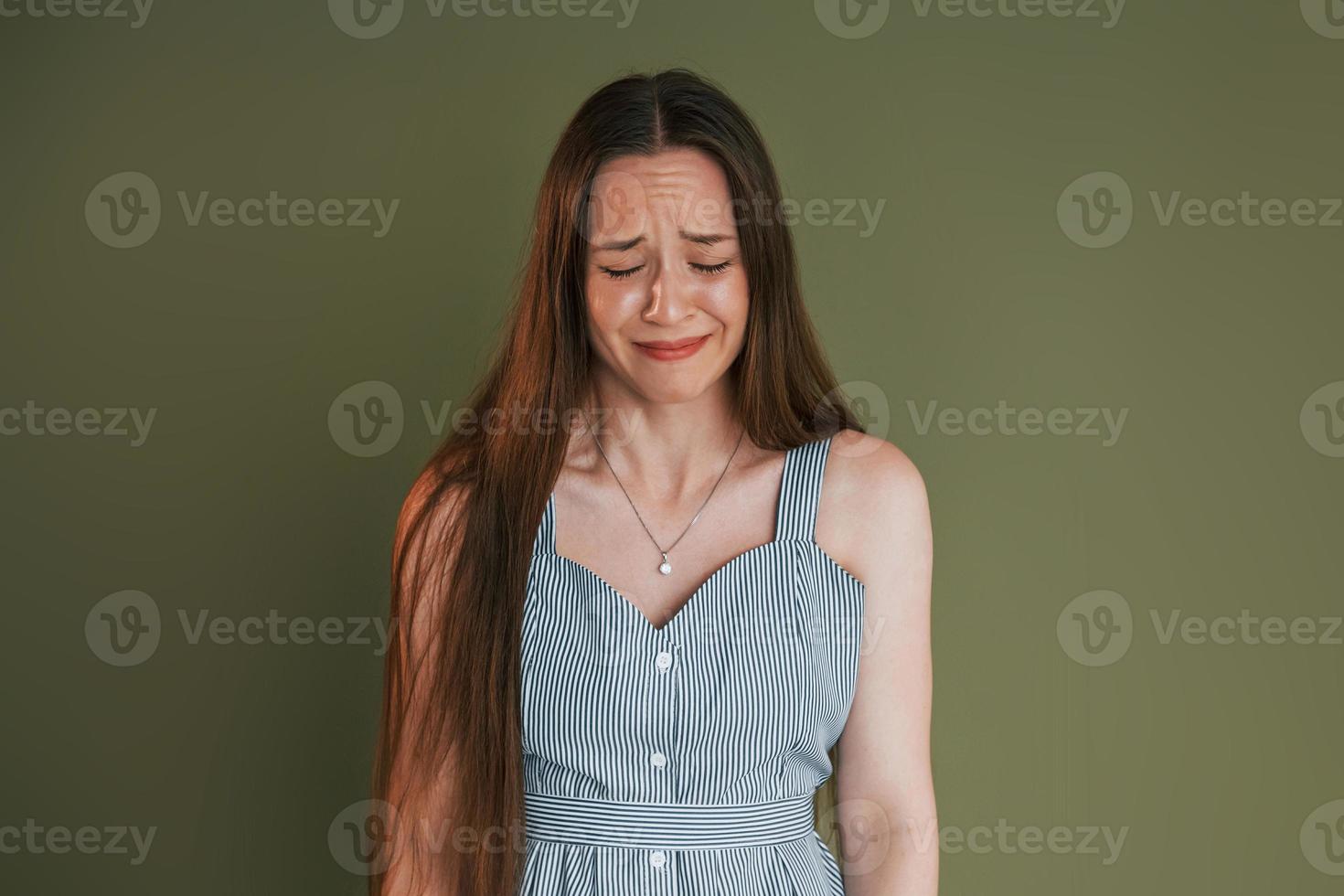 une jeune femme en vêtements décontractés pleure en se tenant à l'intérieur du studio photo