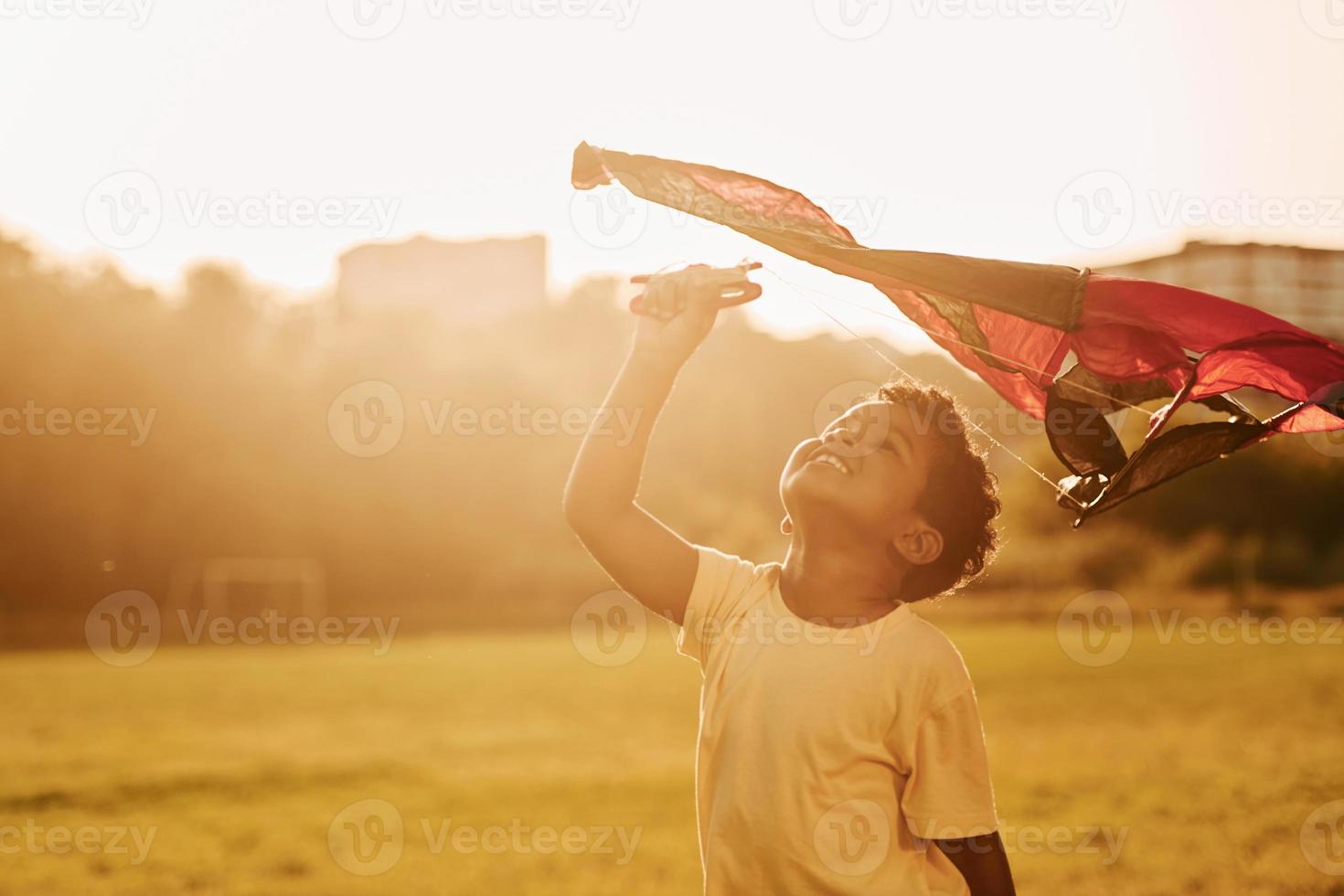 cerf-volant rouge. un enfant afro-américain s'amuse sur le terrain pendant la journée d'été photo