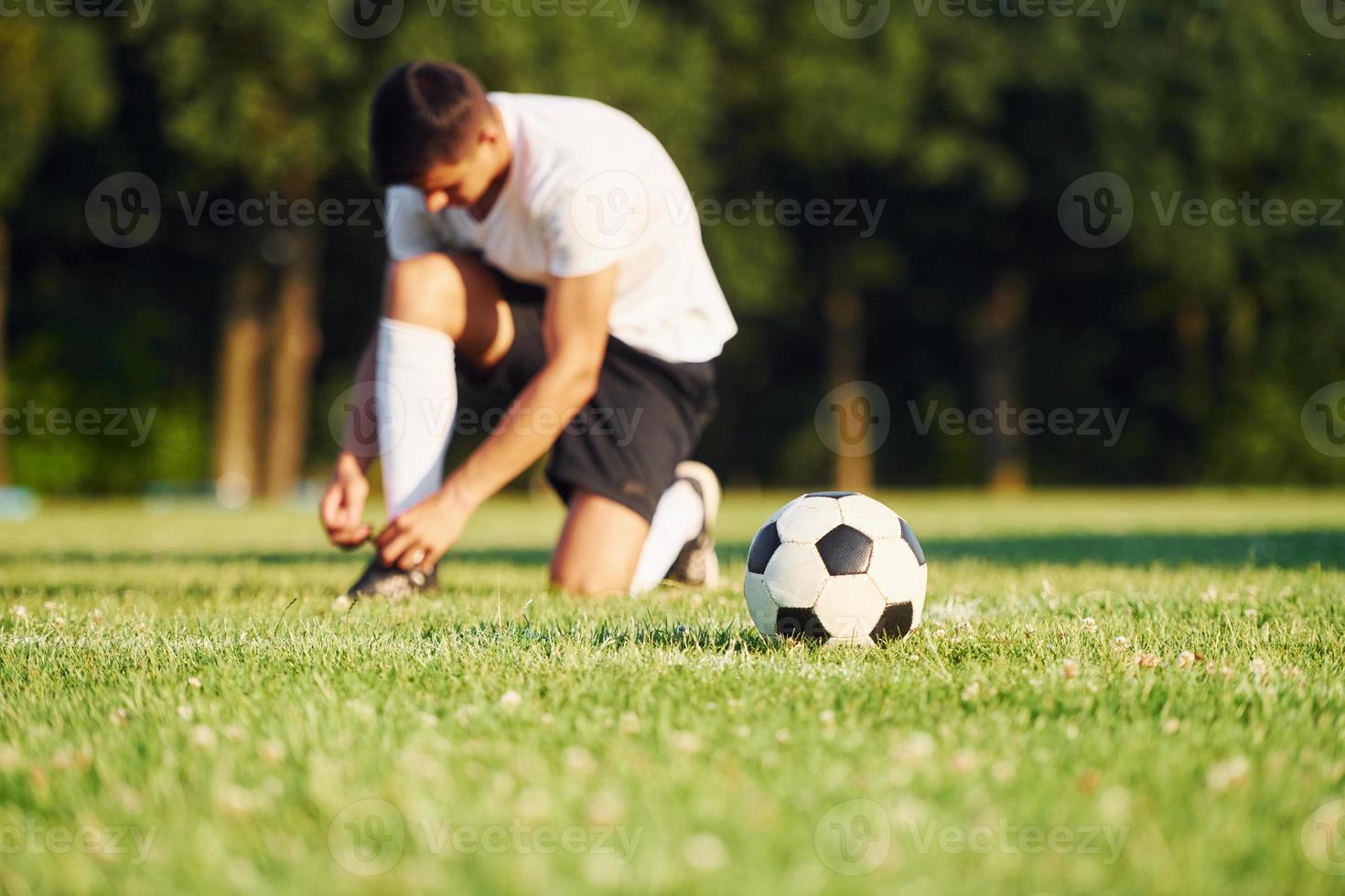 liens lacets. jeune footballeur s'entraîne sur le terrain sportif photo