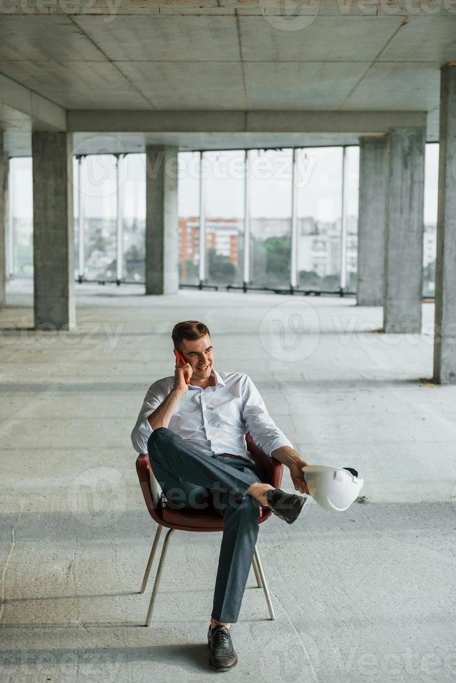 parle par téléphone. un jeune homme en tenue de soirée travaille à l'intérieur sur la construction photo