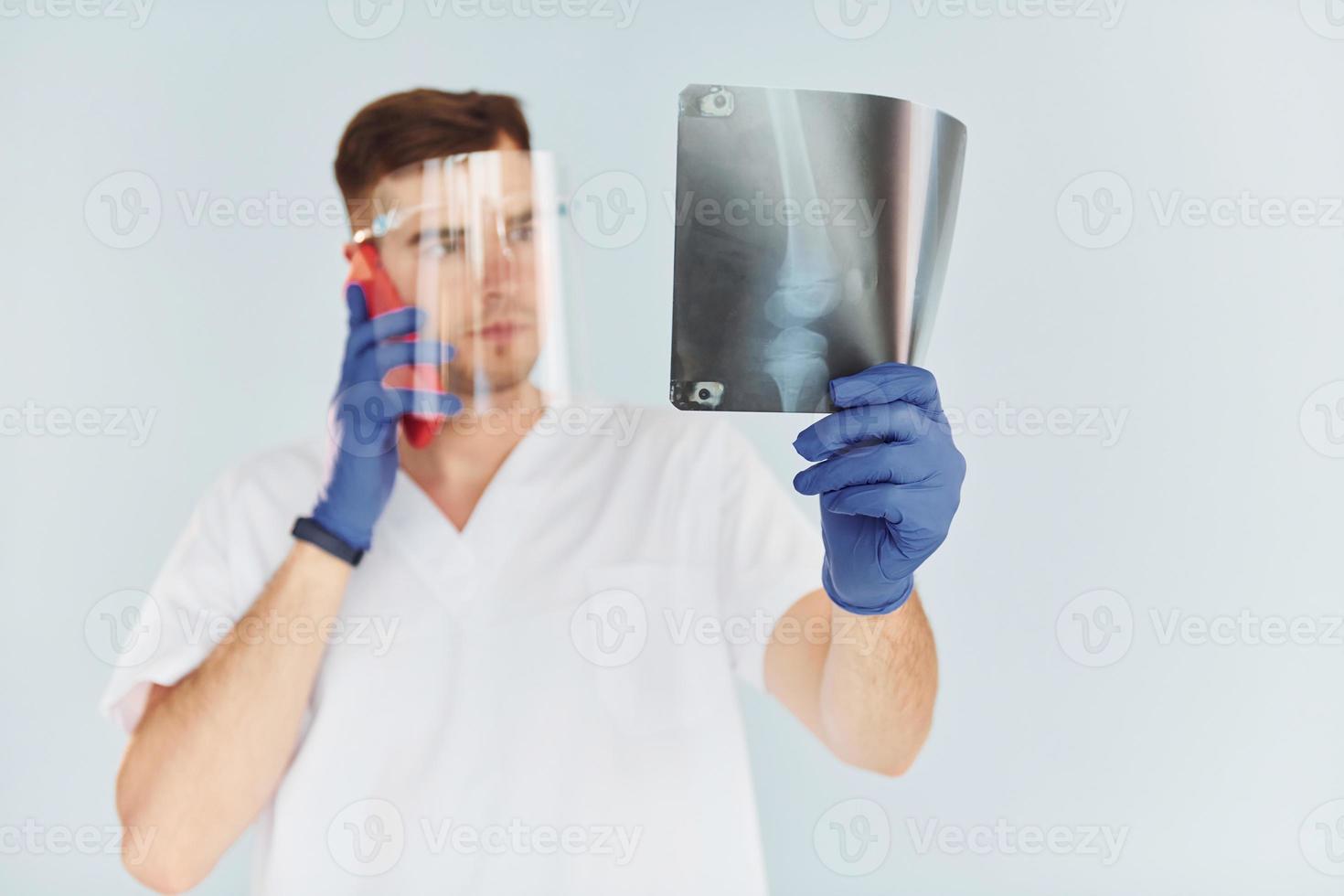 en uniforme blanc. jeune homme médecin est à l'intérieur sur fond blanc photo