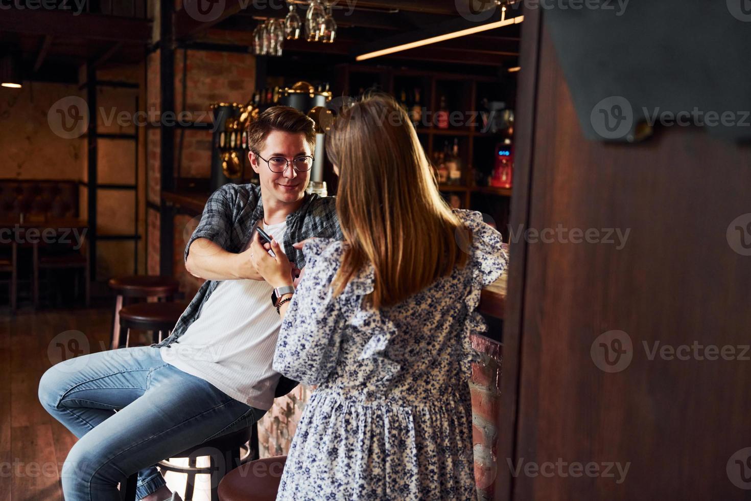jeune homme avec une femme. gens en vêtements décontractés assis dans le pub photo