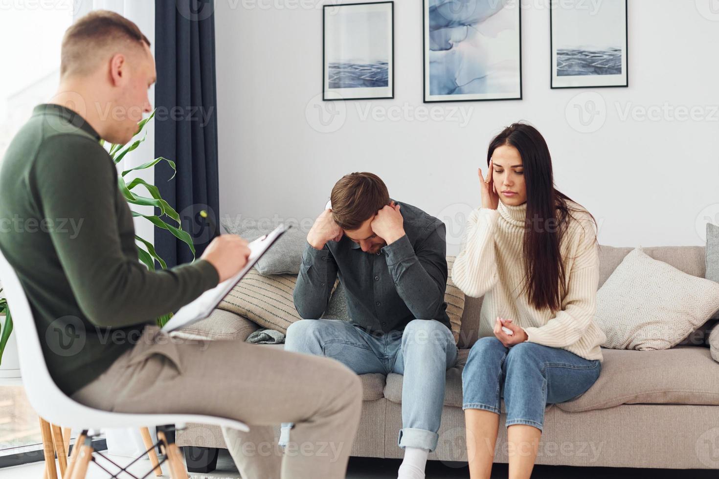 le couple est assis sur le canapé et travaille avec un psychologue masculin photo