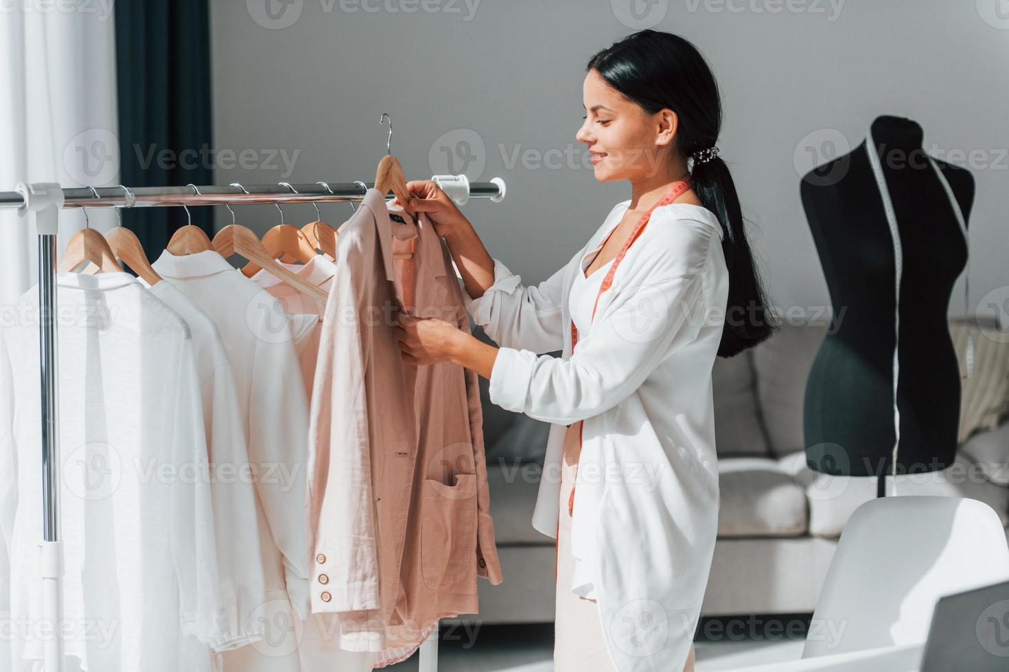 la couturière se tient dans son bureau avec des vêtements différents photo