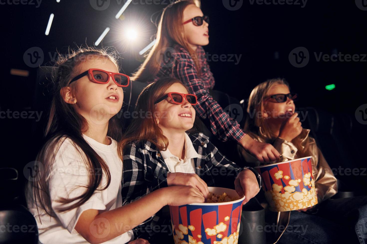 vue de côté. groupe d'enfants assis au cinéma et regardant un film ensemble photo