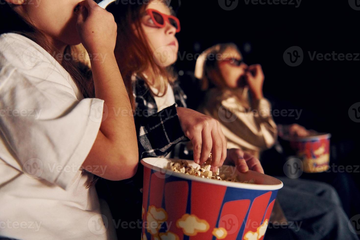 dans des vêtements décontractés. groupe d'enfants assis au cinéma et regardant un film ensemble photo