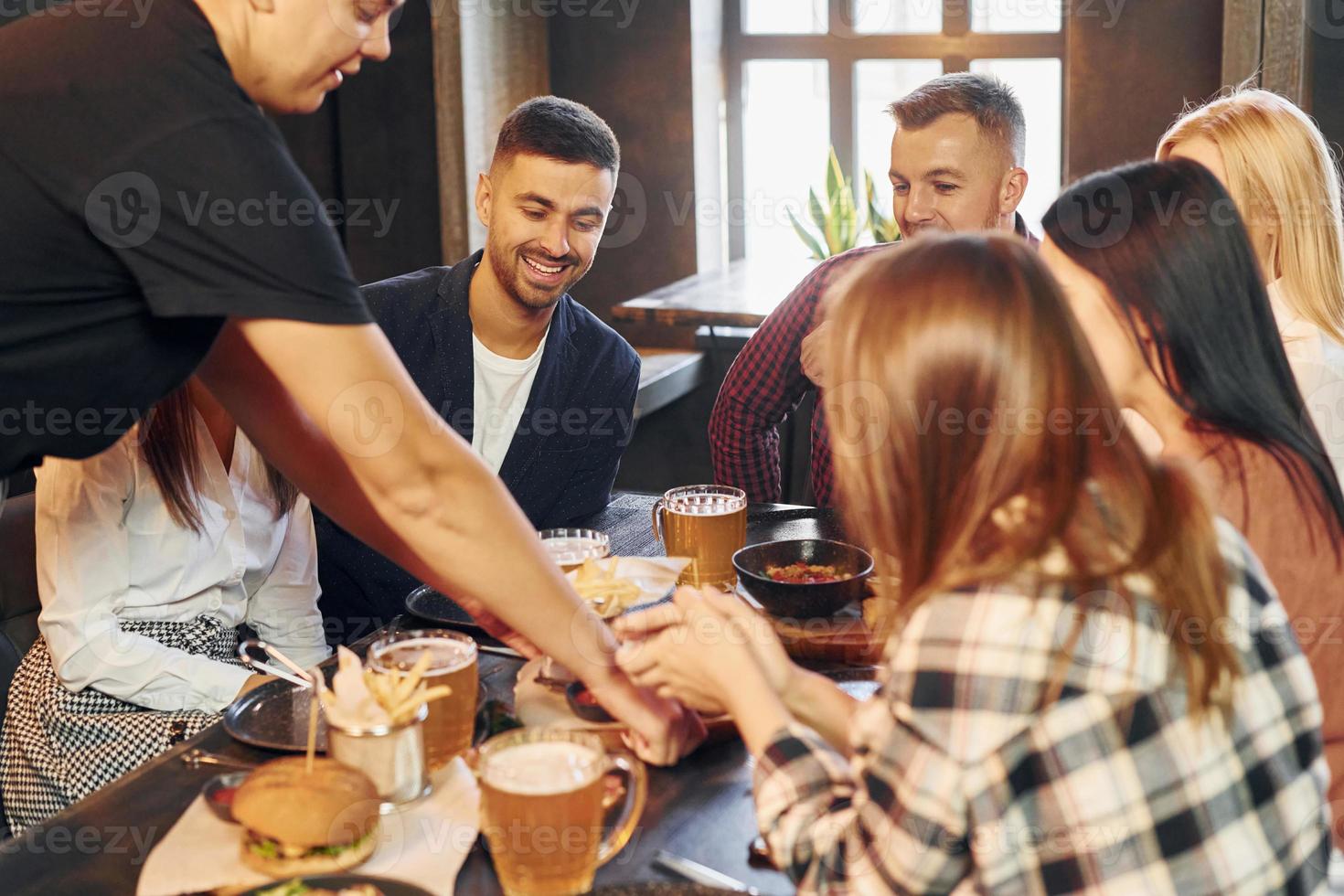 assis et se reposant. groupe de jeunes amis ensemble au bar avec de la bière photo