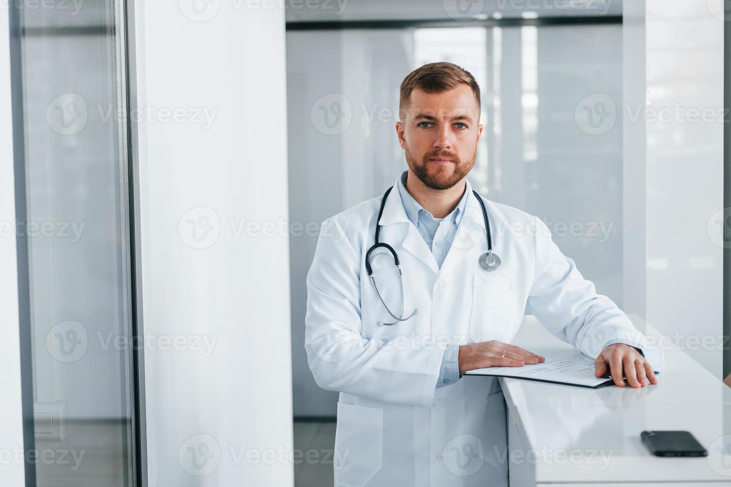 vue de face. médecin professionnel en blouse blanche est à la clinique photo