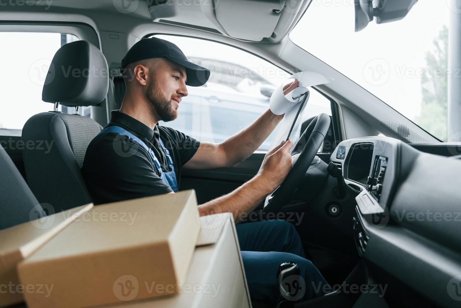 avec véhicule. livreur en uniforme est à l'intérieur avec voiture et avec commande photo