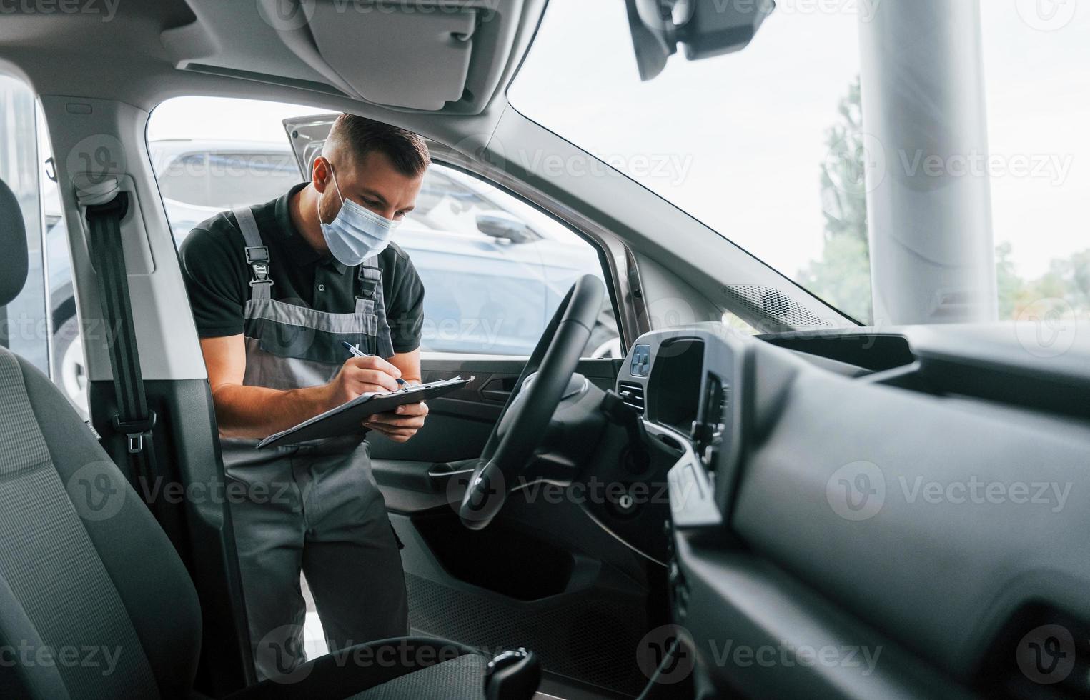 Contrôle de qualité. un homme en uniforme travaille dans l'autosalon pendant la journée photo