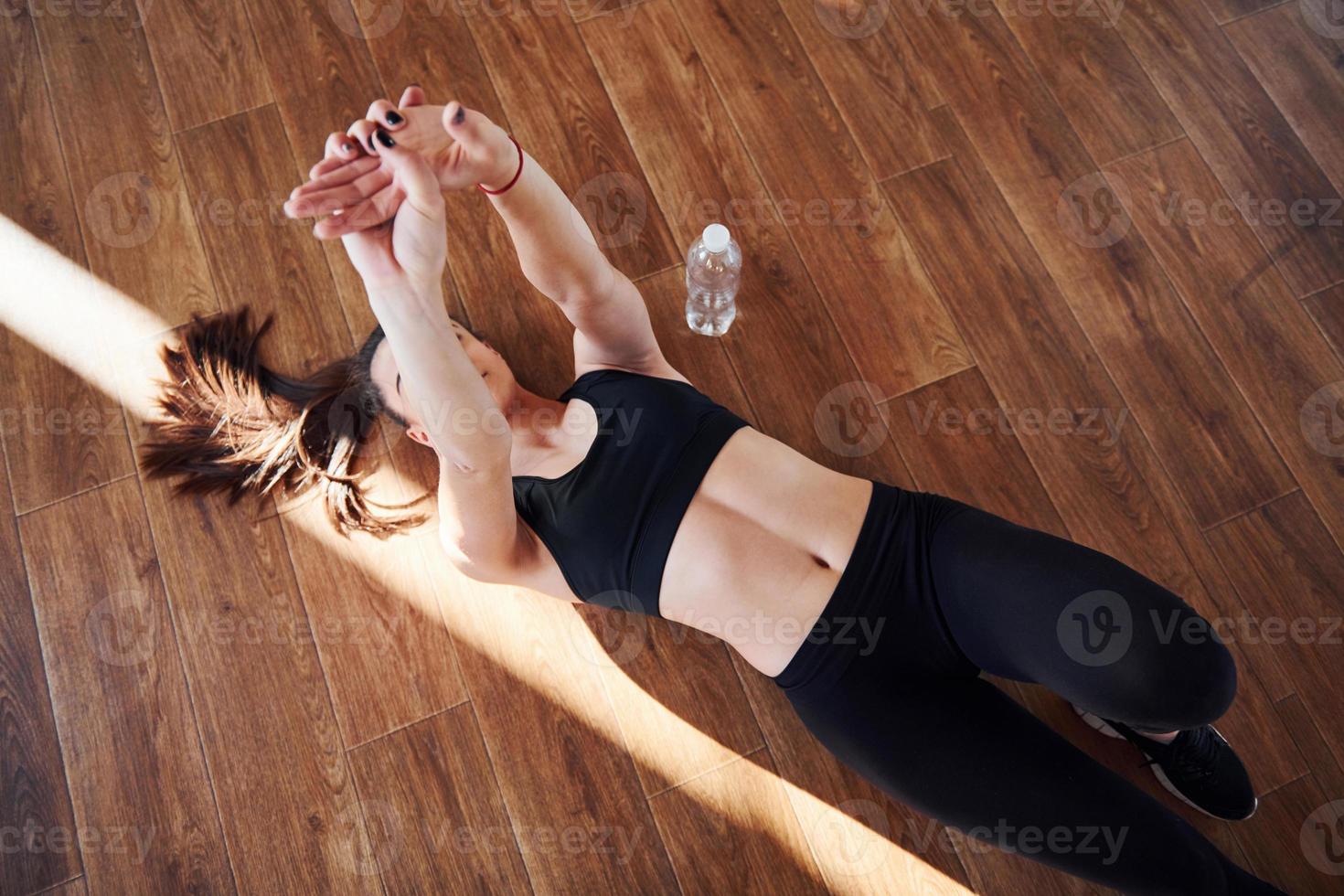 au sol éclairé par des faisceaux lumineux. jeune femme sportive en tenue de sport faisant du fitness dans la salle de sport photo