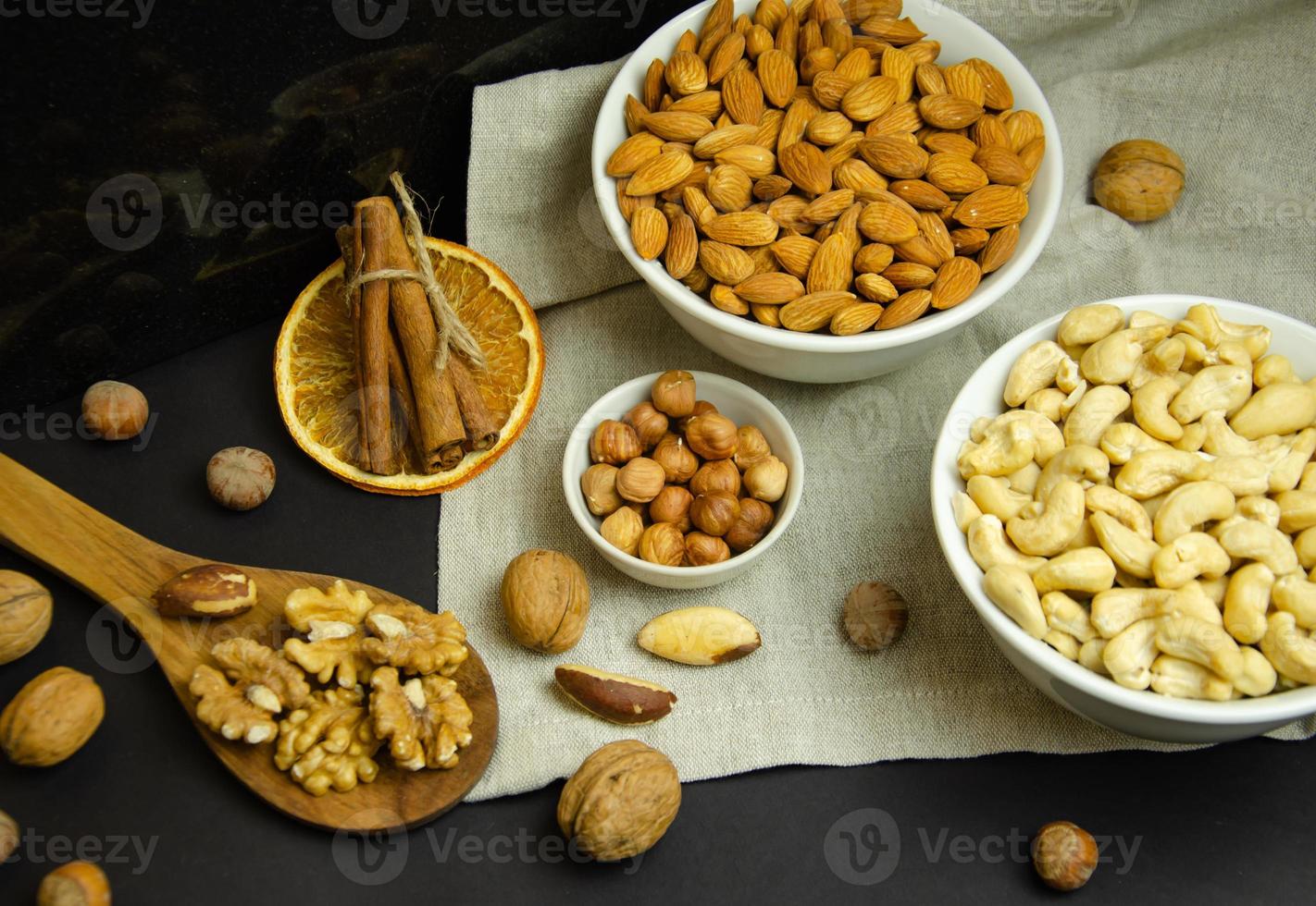 Noix dans différentes assiettes et sur une cuillère en bois, nature morte aux noisettes photo