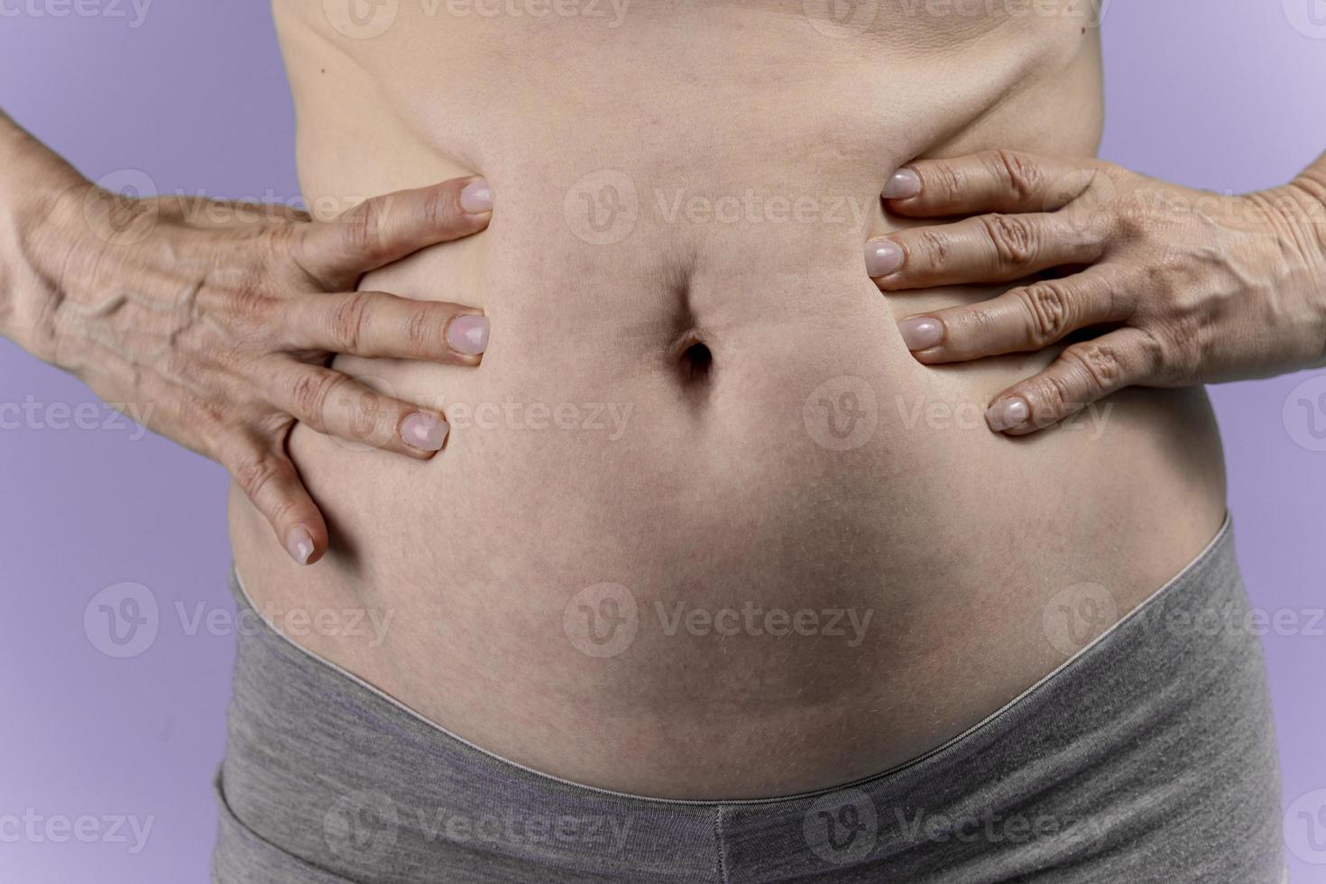 jeune femme souffrant de douleurs abdominales sur fond violet. photo