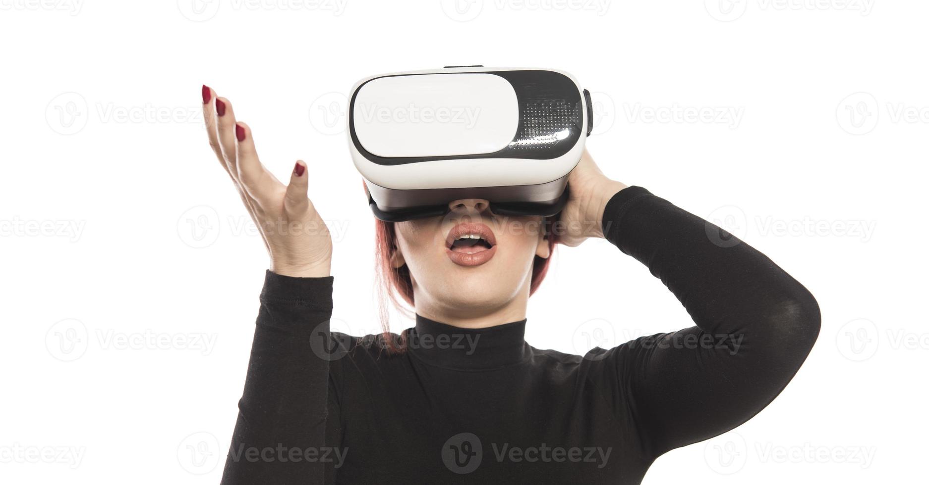 jolie jolie femme excitée dans un casque vr levant les yeux et essayant de toucher des objets dans la réalité virtuelle photo