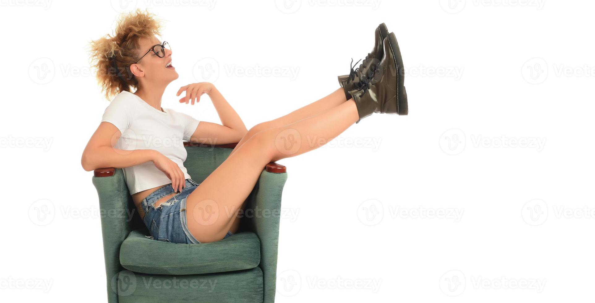 femme blonde folle élégante à la mode, assise sur la chaise et posant devant la caméra en studio. concept de beauté de mode. photo