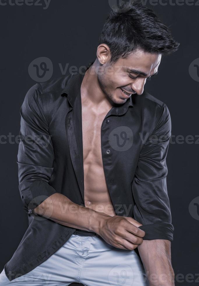 beau modèle masculin arabe avec un corps parfait qui pose en studio. portrait d'un modèle masculin athlétique posant sur fond sombre dans le studio. notion de mode. photo