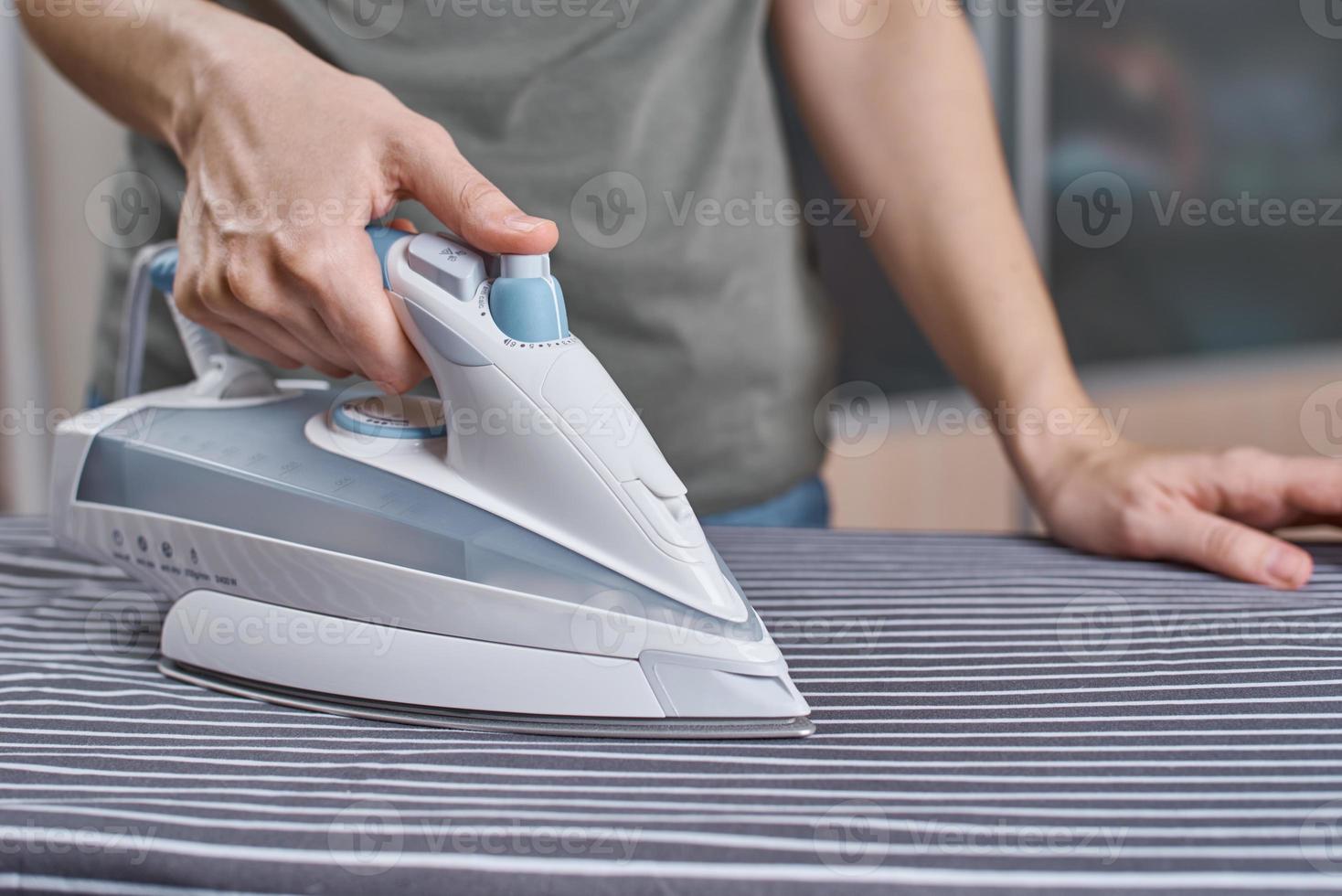 femme repassant des vêtements sur la planche à repasser avec un fer à repasser moderne photo