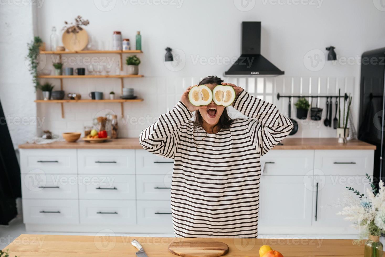 une femme tient des fruits coupés au niveau des yeux au lieu de lunettes photo