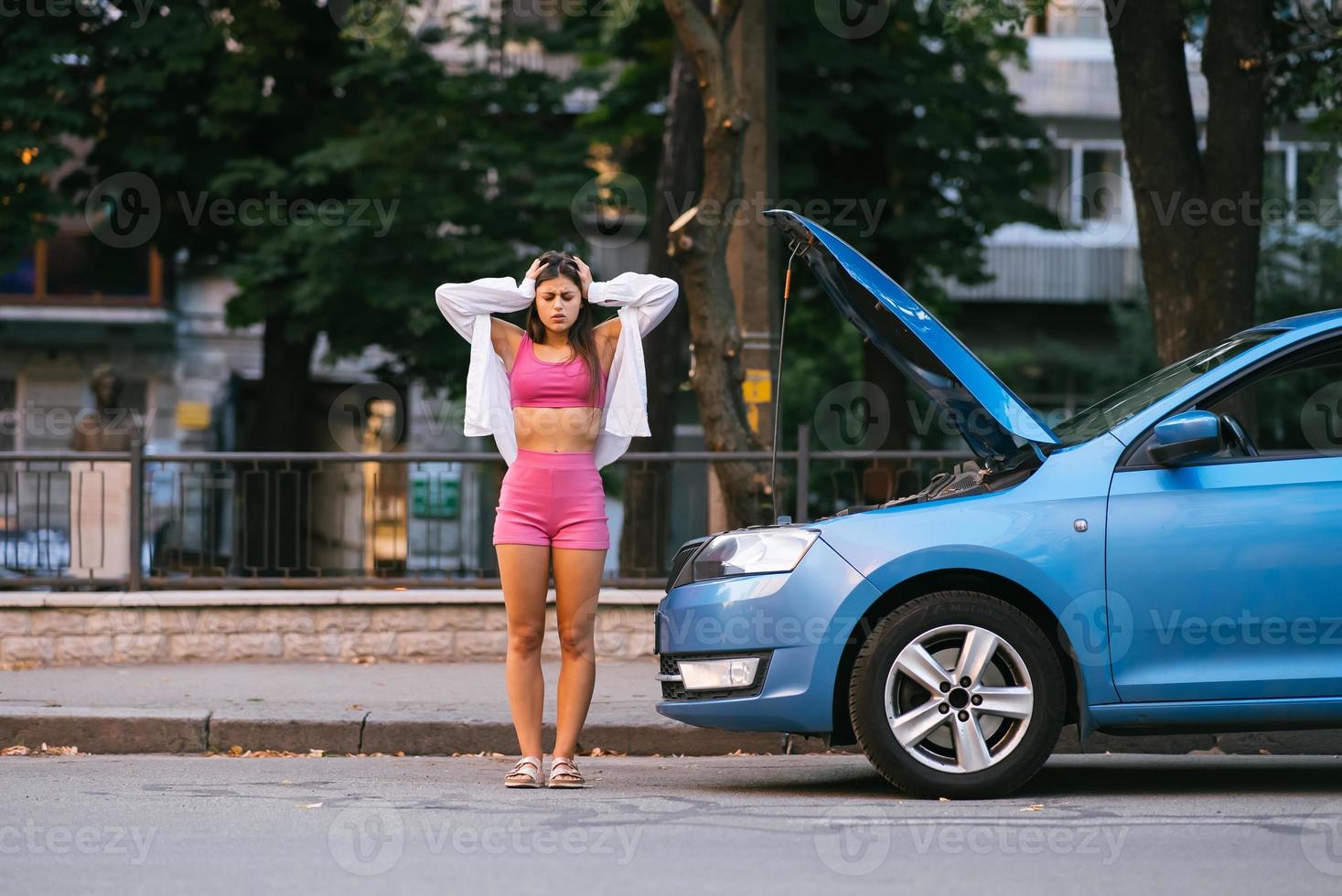 femme avec une voiture cassée sur la route. chercher de l'aide. photo