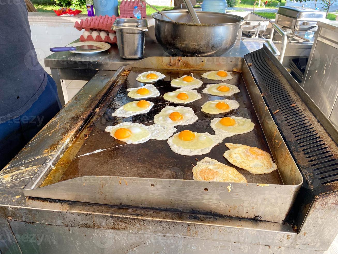 chef, cuisinier cuisine beaucoup d'œufs sur la cuisinière, œufs brouillés dans un restaurant dans une cuisine ouverte dans un hôtel tout compris dans un complexe touristique paradisiaque de pays tropical chaud en vacances photo