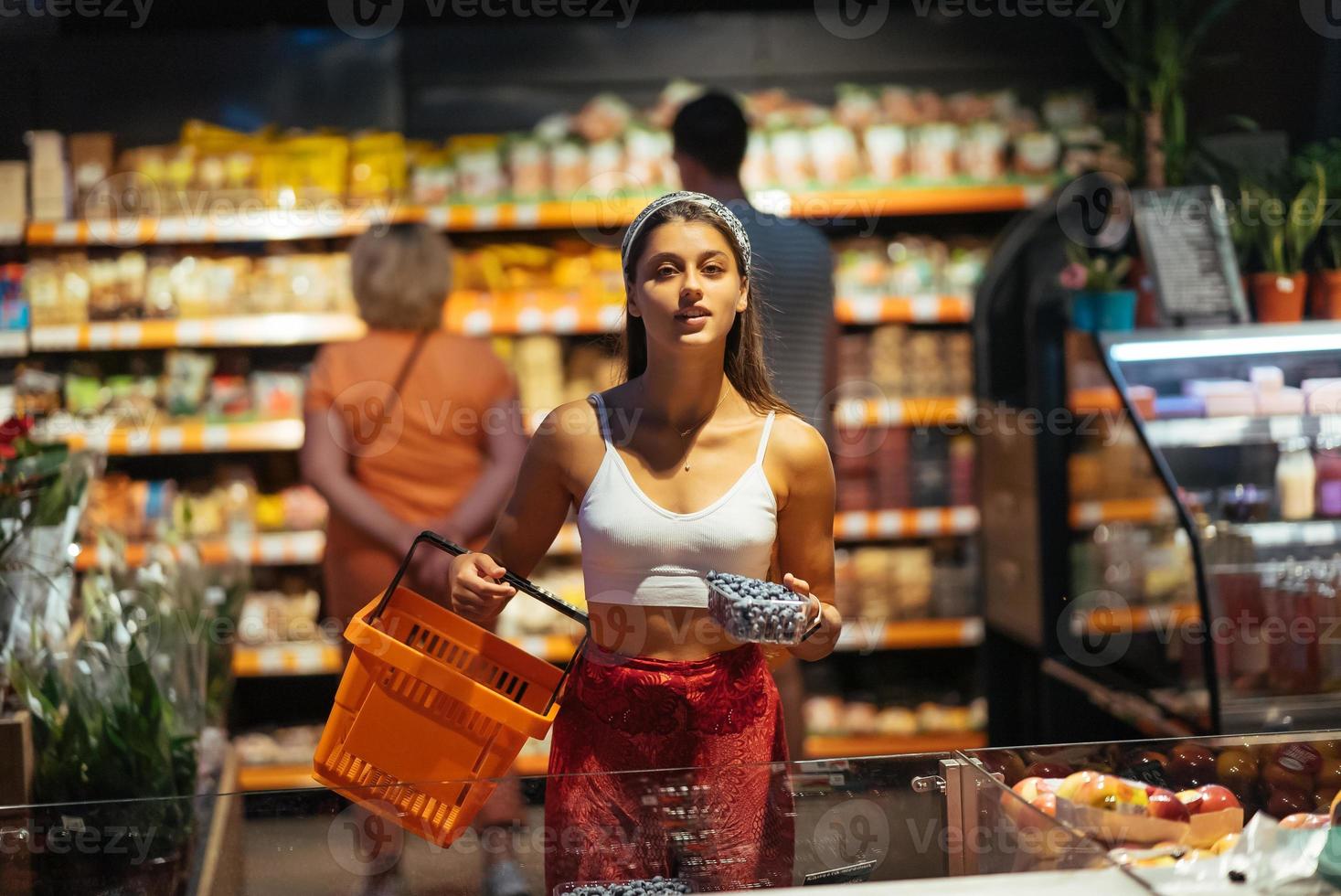 jeune femme fait du shopping au supermarché. choisir la myrtille en magasin photo