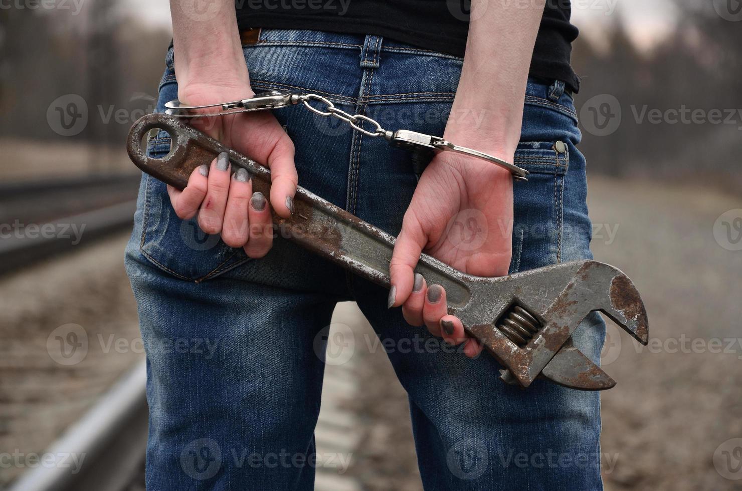 la jeune fille menottée avec la clé à molette sur le fond de la voie ferrée. le concept de prévention de la criminalité avec la participation du chemin de fer et des trains. photo