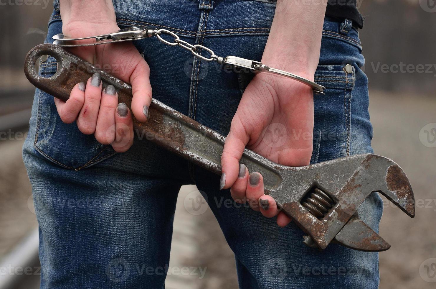 la jeune fille menottée avec la clé à molette sur le fond de la voie ferrée. le concept de prévention de la criminalité avec la participation du chemin de fer et des trains. photo