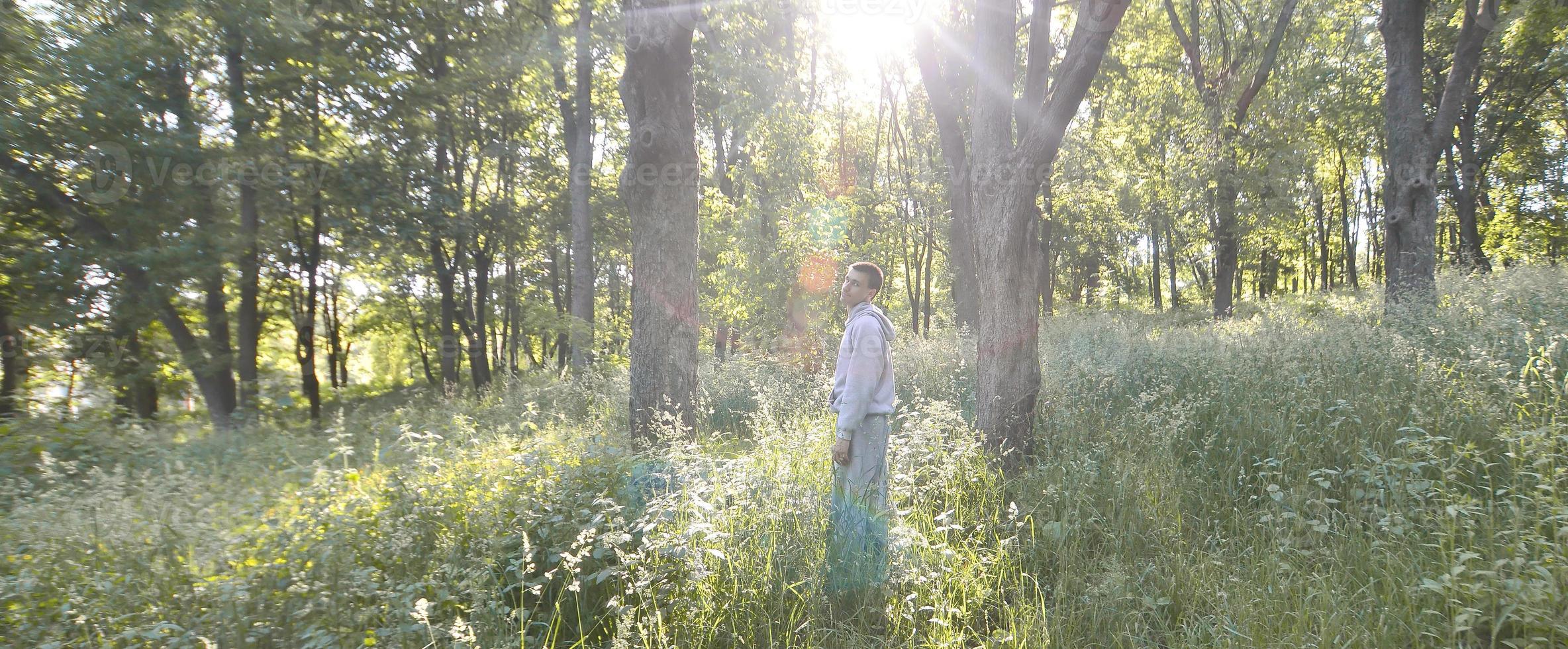 un jeune homme en costume de sport gris se tient en face du soleil parmi photo