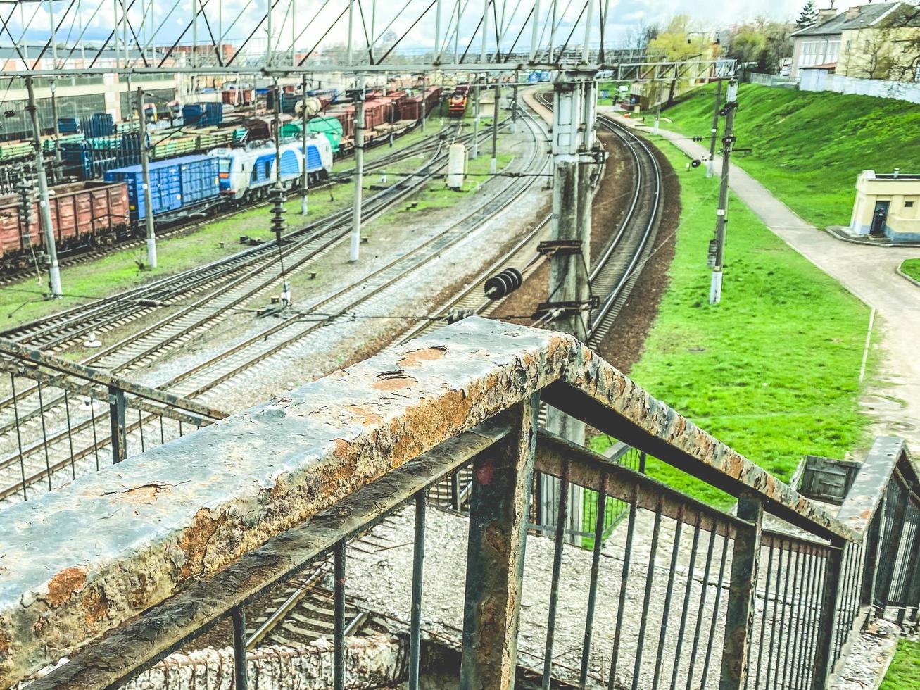 chemin de fer dans la ville. vieille route rouillée sous le pont. les balustrades du pont sont peintes avec de la peinture et recouvertes de rouille. rails en métal photo