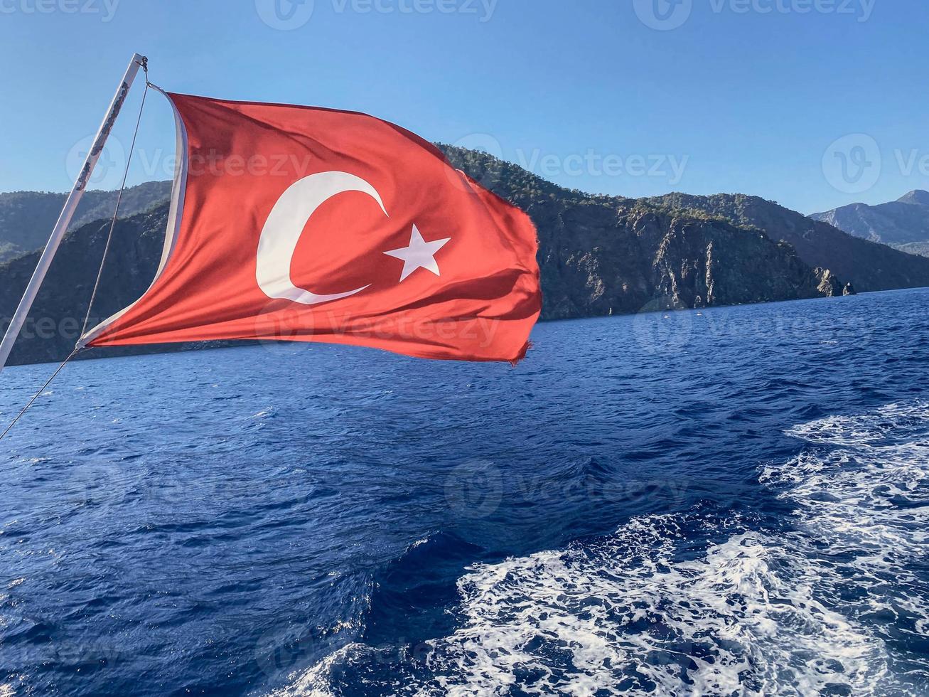 mer dans un pays chaud et tropical. l'eau à côté des montagnes fleuries avec des plantes et de la verdure. sur le fond du ciel bleu et du drapeau de la turquie photo