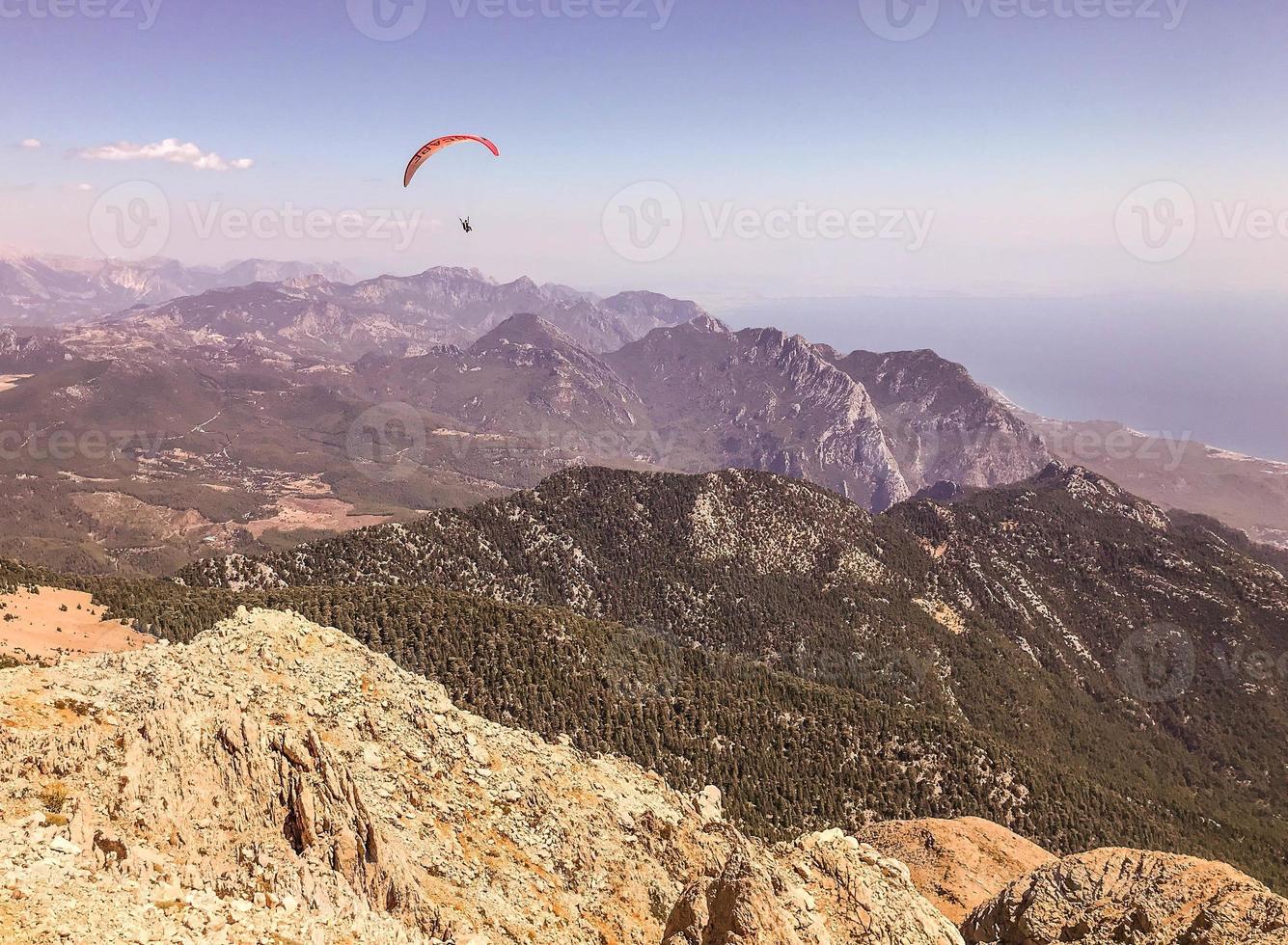 montagnes contre le ciel bleu. l'herbe et les buissons poussent sur la montagne. loisirs. le parapente vole dans le ciel. voyage aérien en montgolfière photo