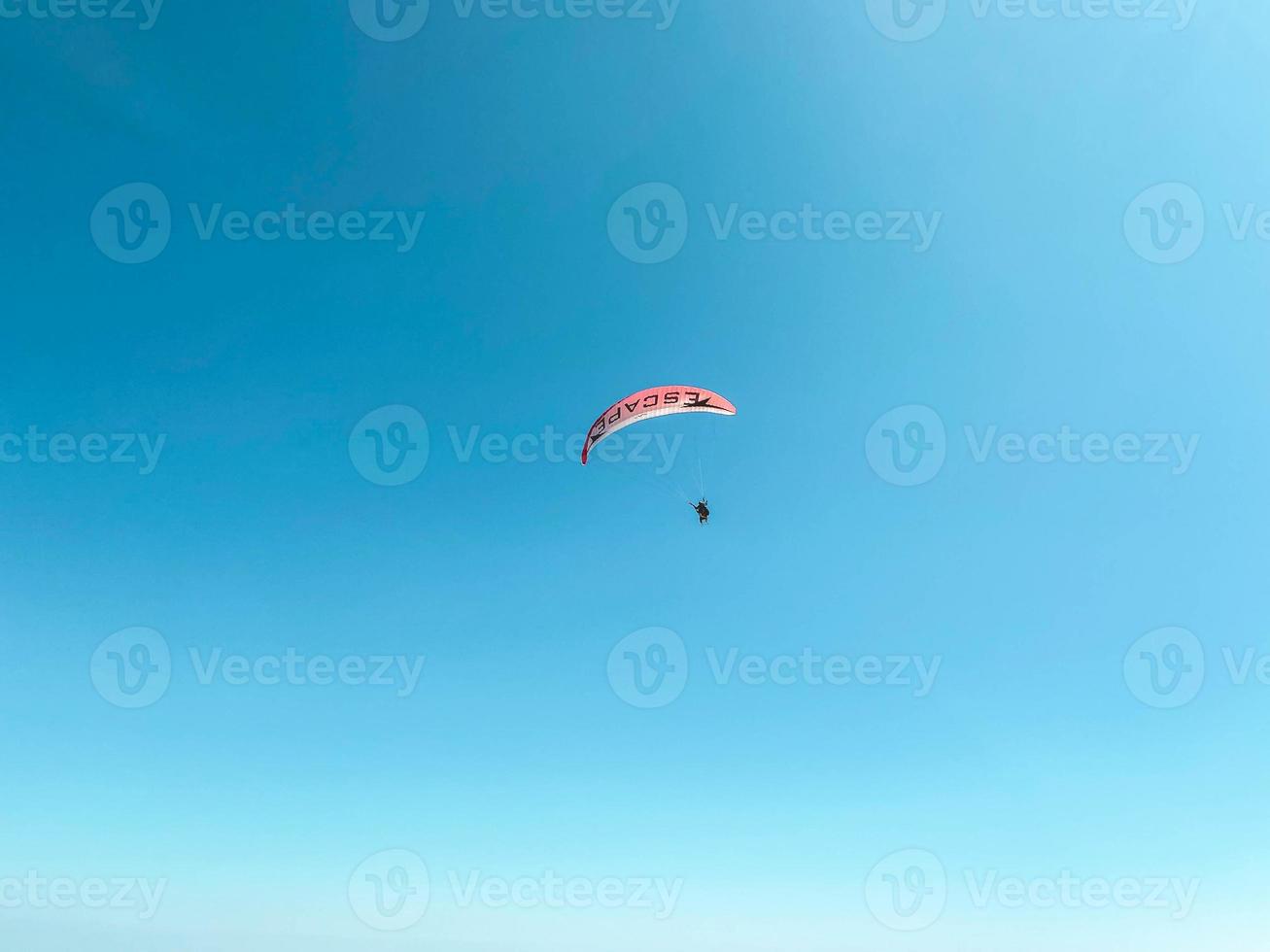 les parachutistes volent dans les airs. sauter en parapente. vue de la ville d'une hauteur de vol. parachute rouge. divertissement extrême photo