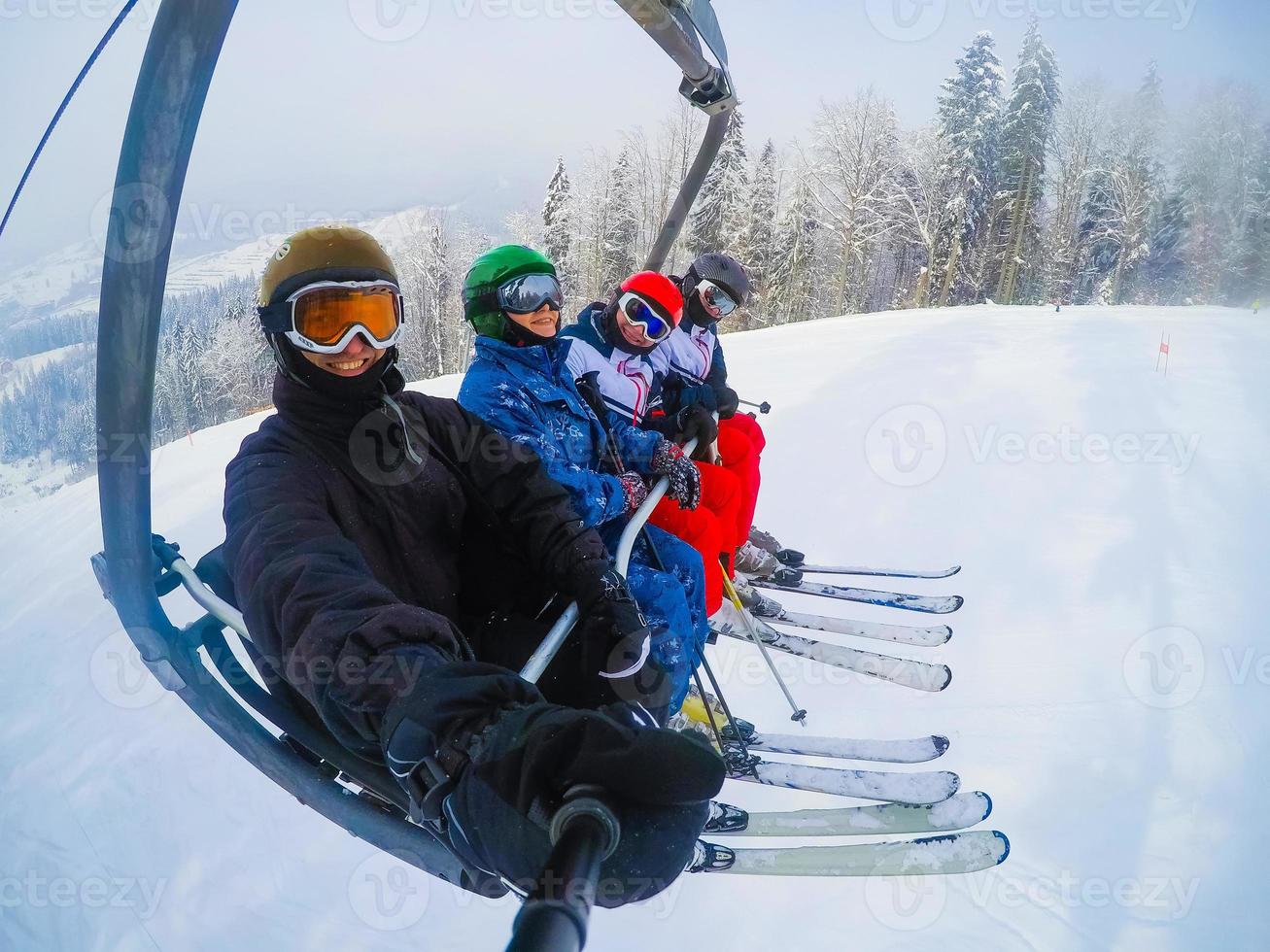 joyeux jeunes amis skieurs sur les remontées mécaniques monter sur la piste de ski au jour de neige photo