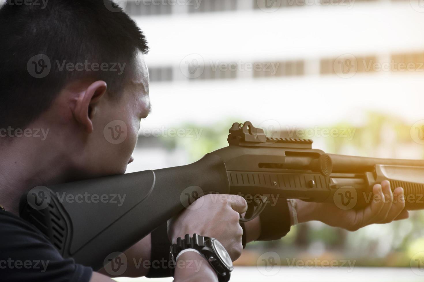 fusil de chasse tenant dans les mains du tireur et regardant vers la cible de tir, mise au point douce et sélective, concept pour pratiquer le tir au fusil de chasse pour protéger la vie humaine. photo