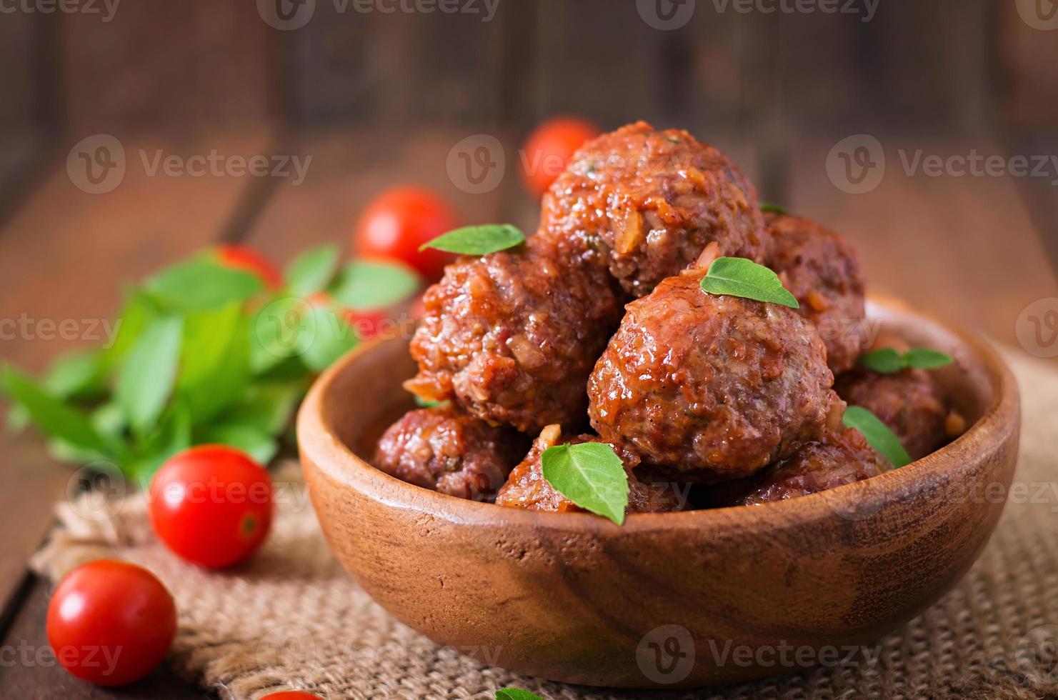 boulettes de viande à la sauce tomate aigre-douce et basilic dans un bol en bois photo