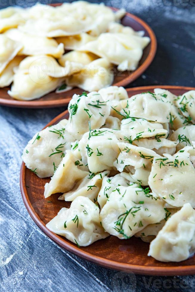 pelmeni ou raviolis russes traditionnels, boulettes de viande sur fond noir en bois. cuisine russe et concept de cuisine russe. photo