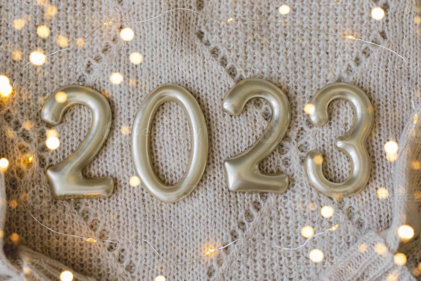 Numéros 2023 en nombre d'or sur pull tricoté beige en arrière-plan. bonne année 2022, noël, concepts de vacances confortables. vue de dessus, mise à plat photo