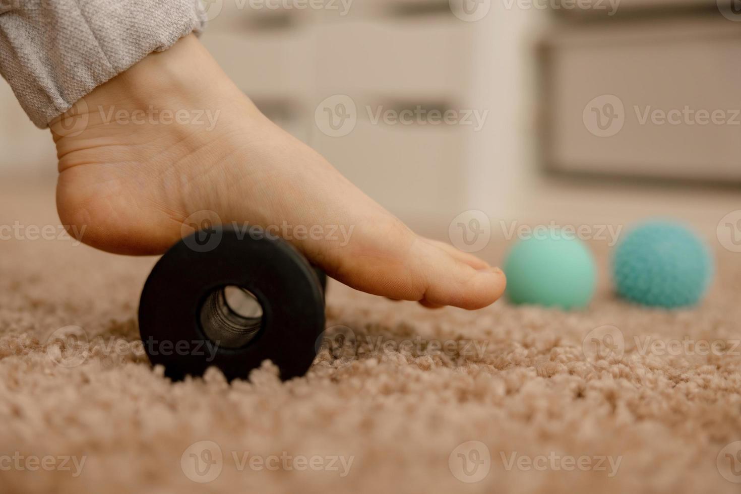 femme faisant un exercice de gymnastique de correction des pieds plats à l'aide d'un rouleau de massage. relaxation myofasciale des muscles du pied. hallux valgus. la douleur. identification des pieds plats. pratiques d'auto-soins à la maison, santé. photo