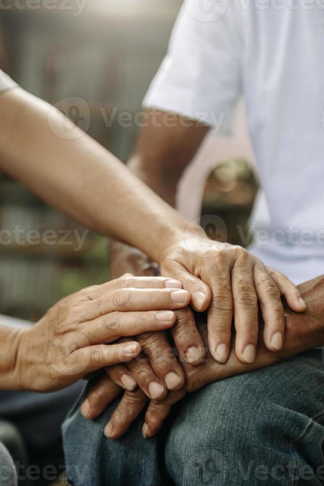 mains du vieil homme et une main de femme sur la table en bois photo