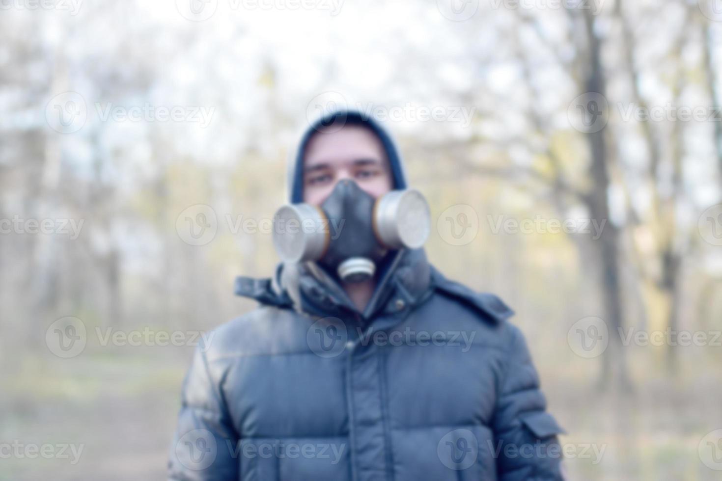 Portrait flou de jeune homme en masque à gaz de protection à l'extérieur en bois de printemps photo