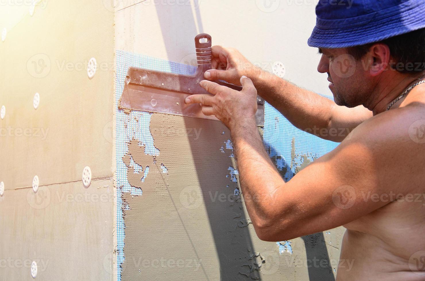 Ouvrier manuel de cinquante ans avec des outils de plâtrage de mur rénovant la maison. plâtrier rénovant les murs et les coins avec une spatule et du plâtre. installation de purée murale. travaux de finition du bâtiment photo