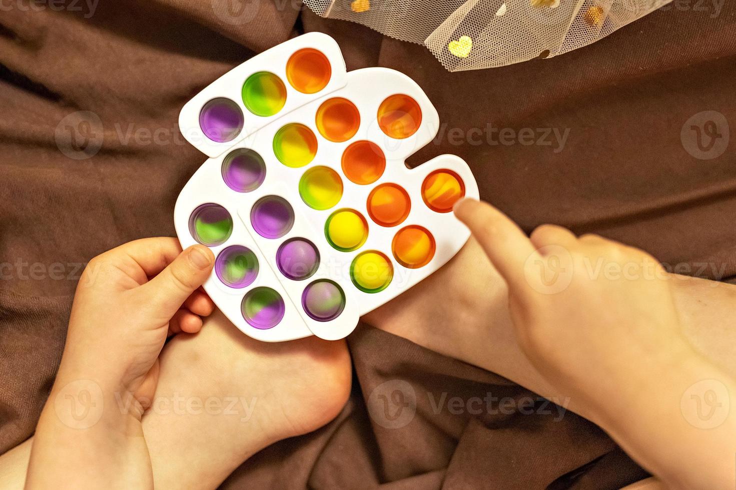 pop it est un jouet anti-stress multicolore entre les mains des enfants.  jeu de bulles. jouets anti-stress. 15601552 Photo de stock chez Vecteezy