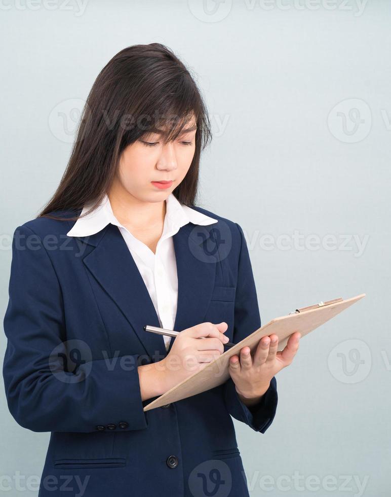 femme asiatique cheveux longs et costume avec presse-papiers et stylo dans les mains photo