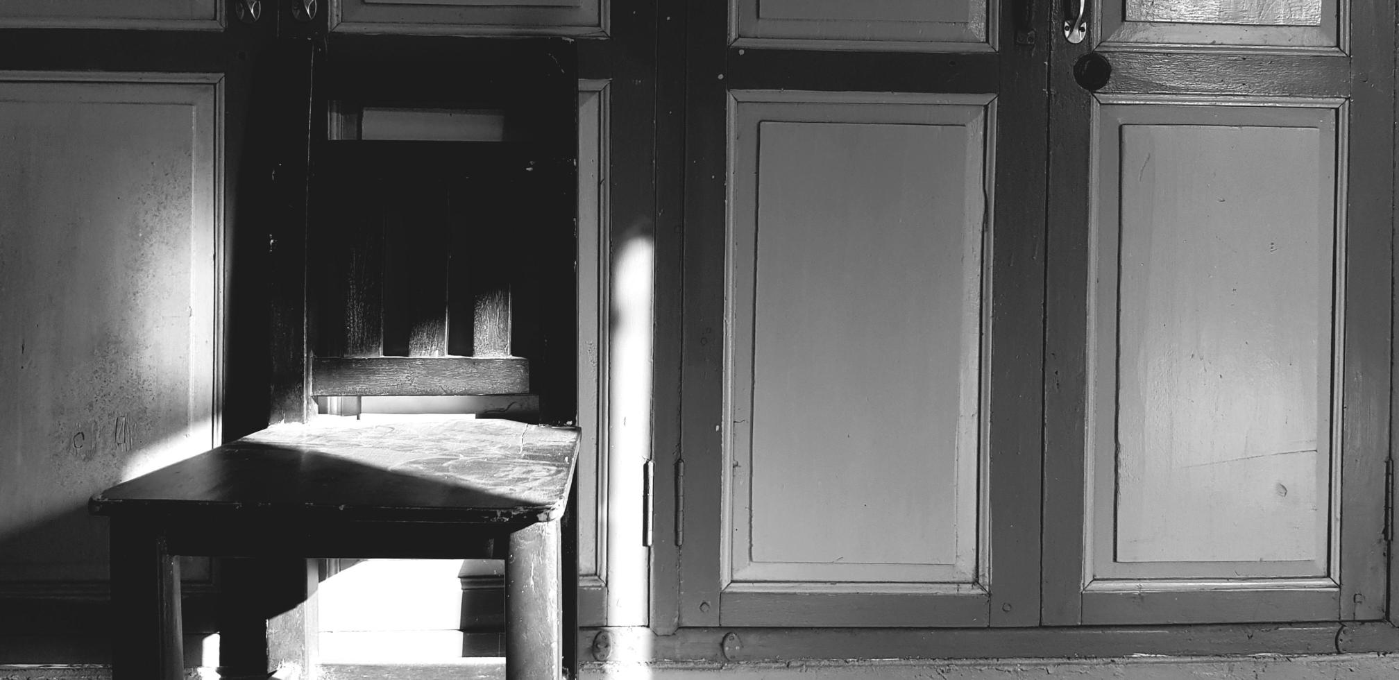 chaise en bois avec ombre de soleil sur porte vintage ou classique en ton noir et blanc ou monochrome. objet rétro avec lumière le matin. photo