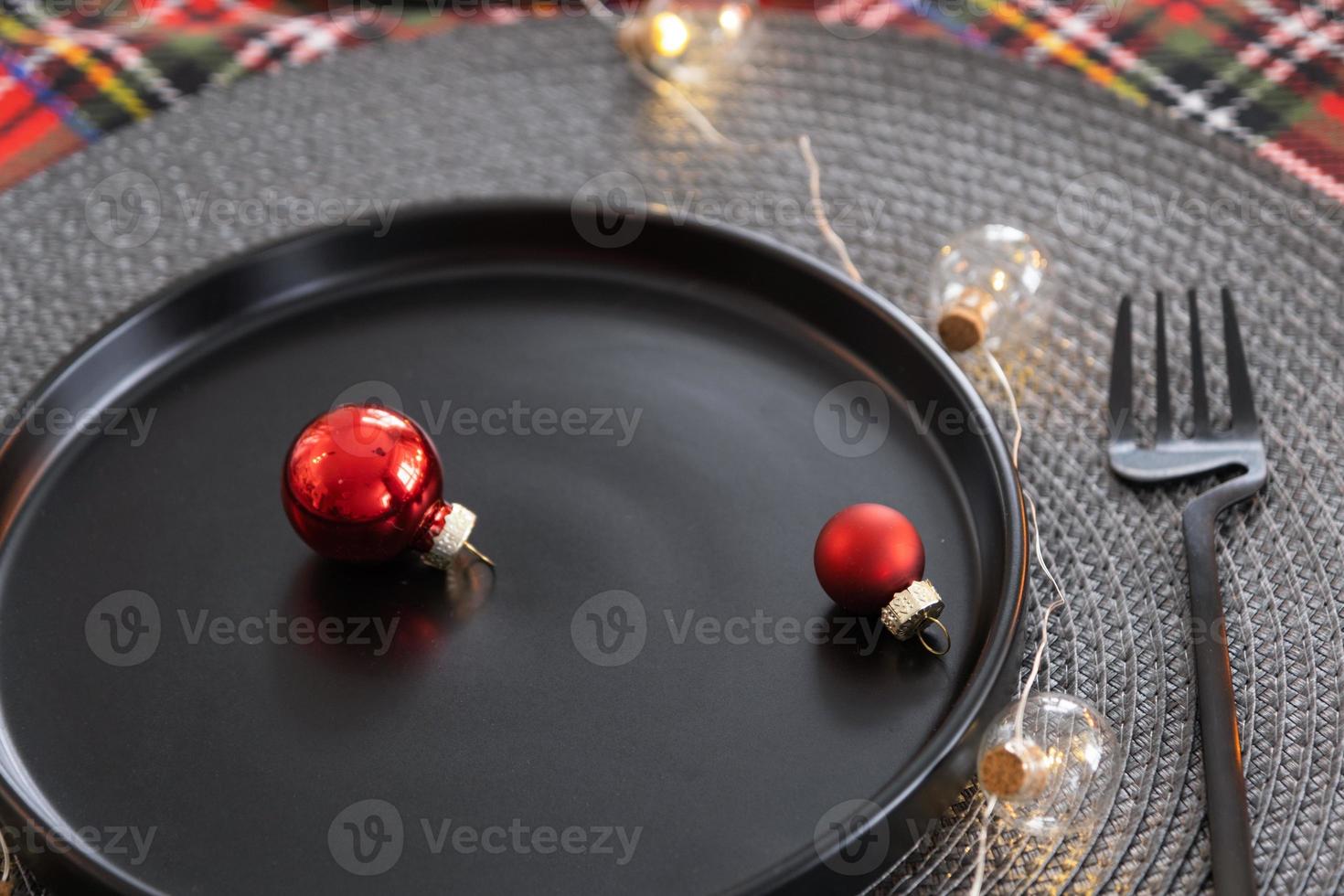 table de fête dressée dans le salon pour noël et nouvel an dans un style loft. sapin de noël, assiettes et fourchettes noires, serviettes tissées, vaisselle tendance, intérieur cosy de la maison photo