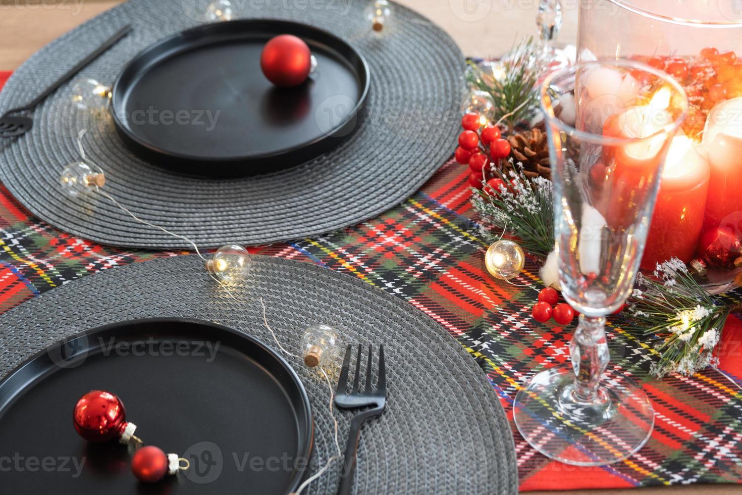 table de fête dressée dans le salon pour noël et nouvel an dans un style loft. sapin de noël, assiettes et fourchettes noires, serviettes tissées, vaisselle tendance, intérieur cosy de la maison photo